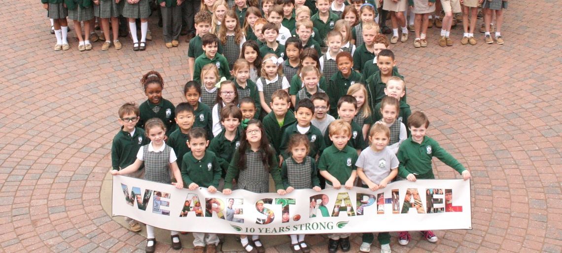 A large group of children holding a banner that says we are st. raphael