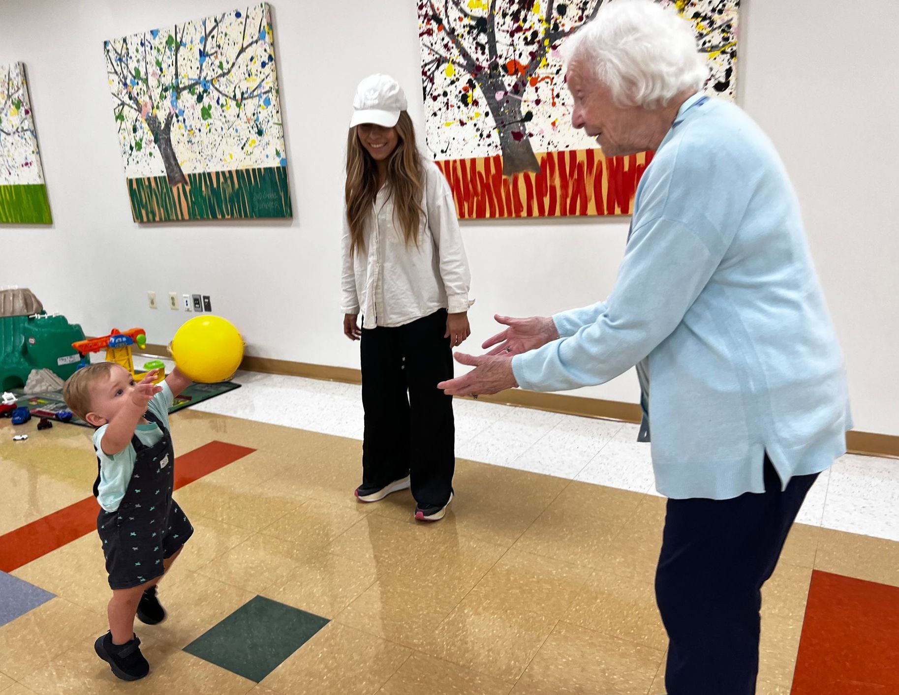 A woman and child are playing with a yellow ball