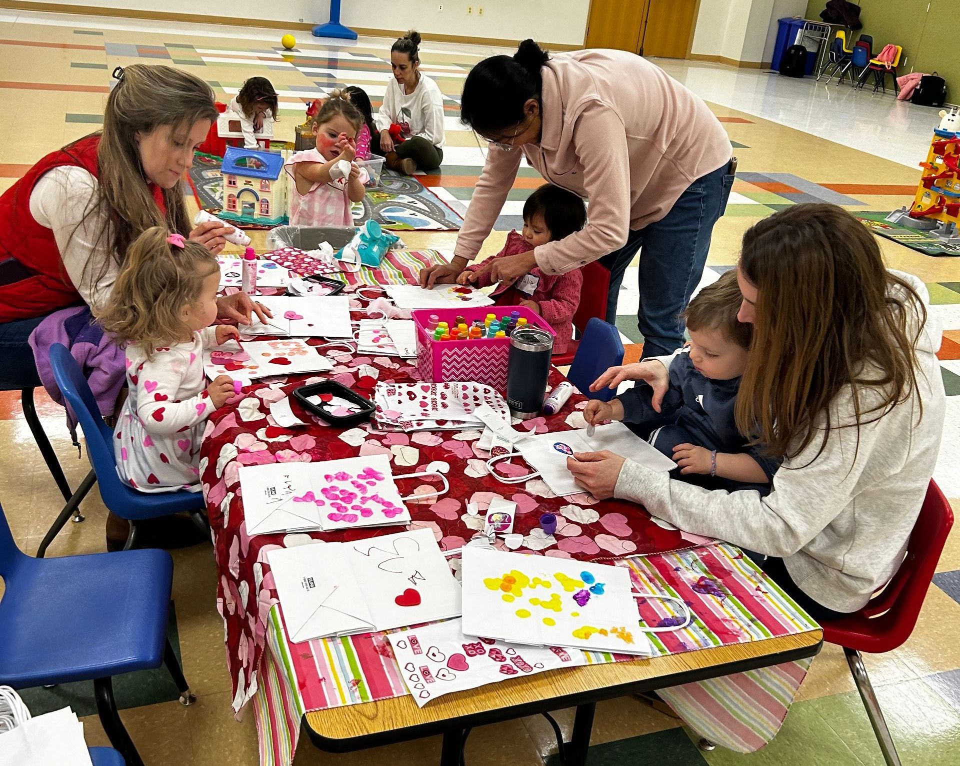 moms sitting at table with toddlers doing a craft