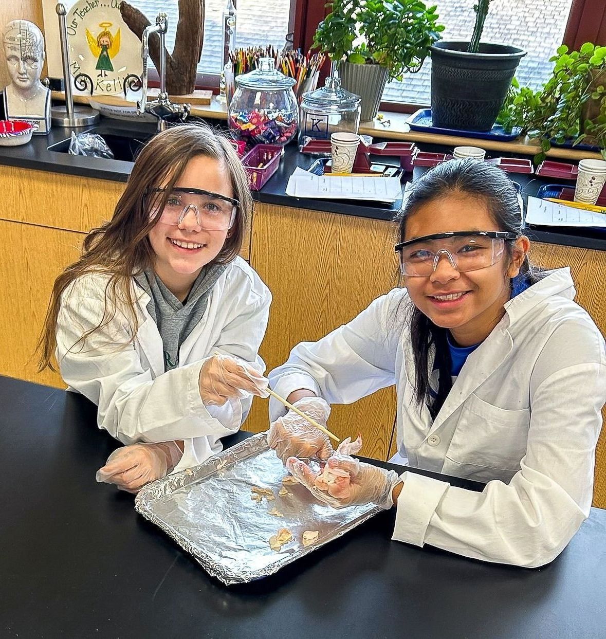 A person wearing a lab coat and goggles is working on a piece of meat