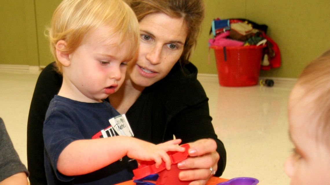 A woman and child are playing with a red object