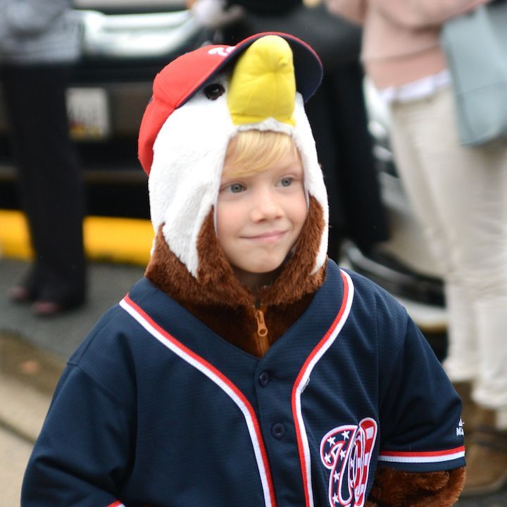 A young boy wearing a baseball uniform and an eagle hat