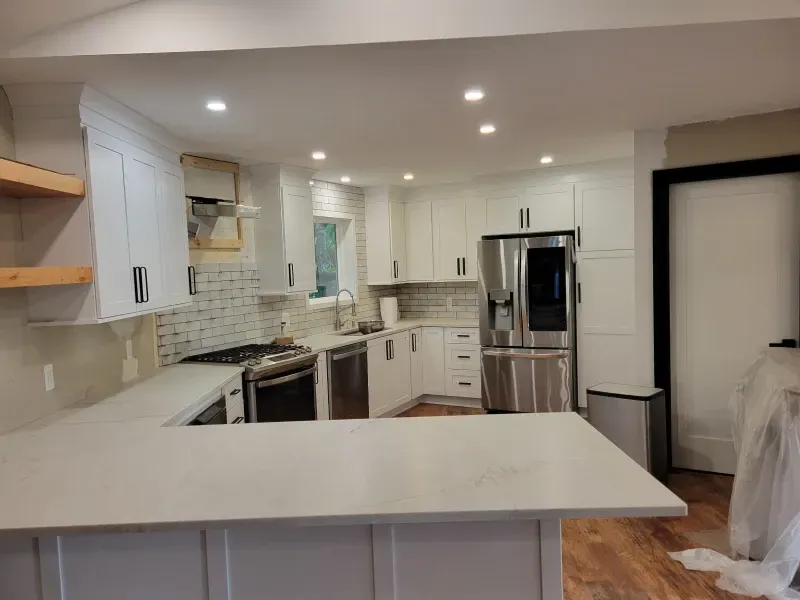 White kitchen with stainless steel appliances, white cabinets, and light countertops.