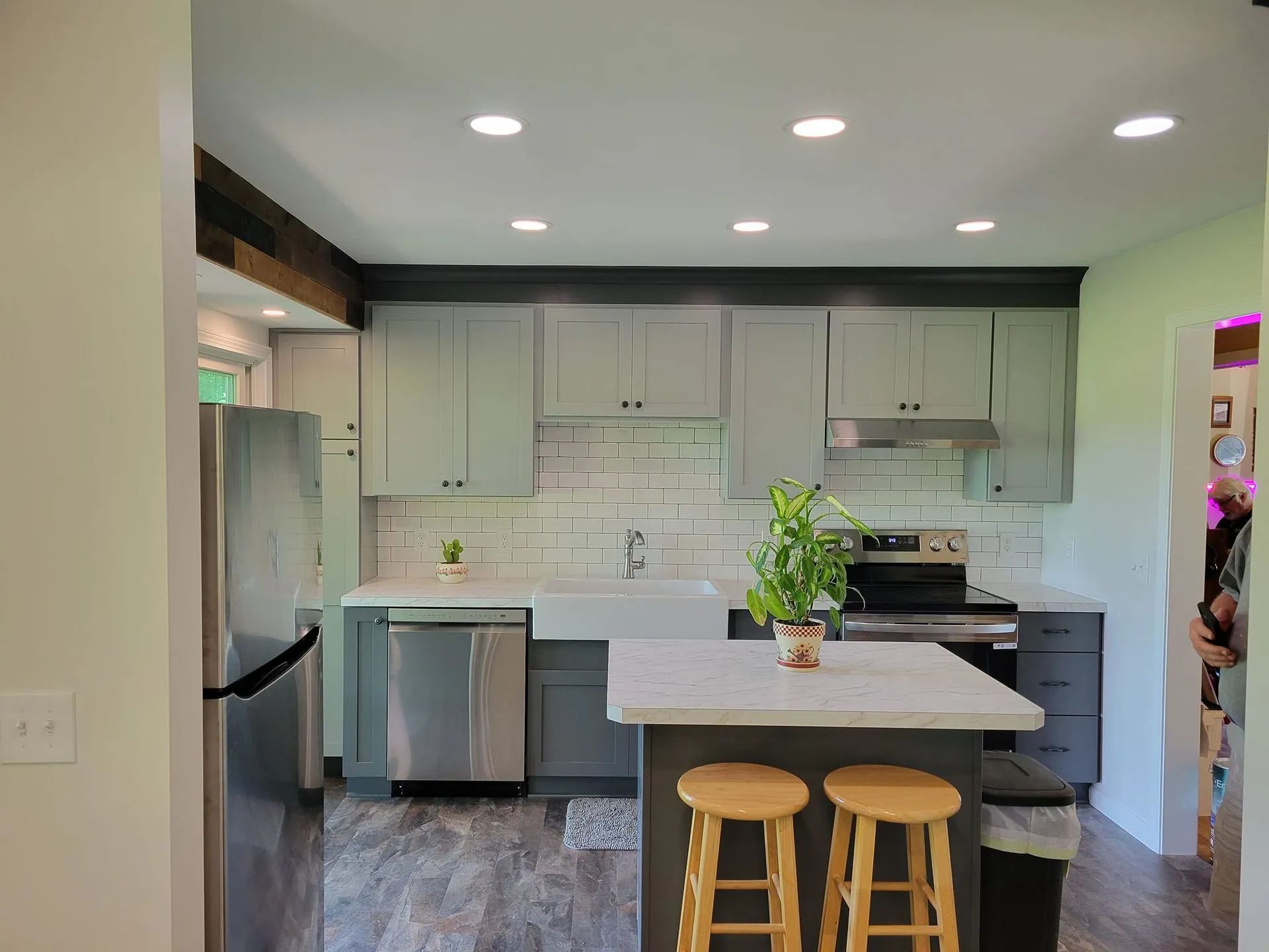 Kitchen with gray cabinets, stainless steel appliances, and a small island with stools.