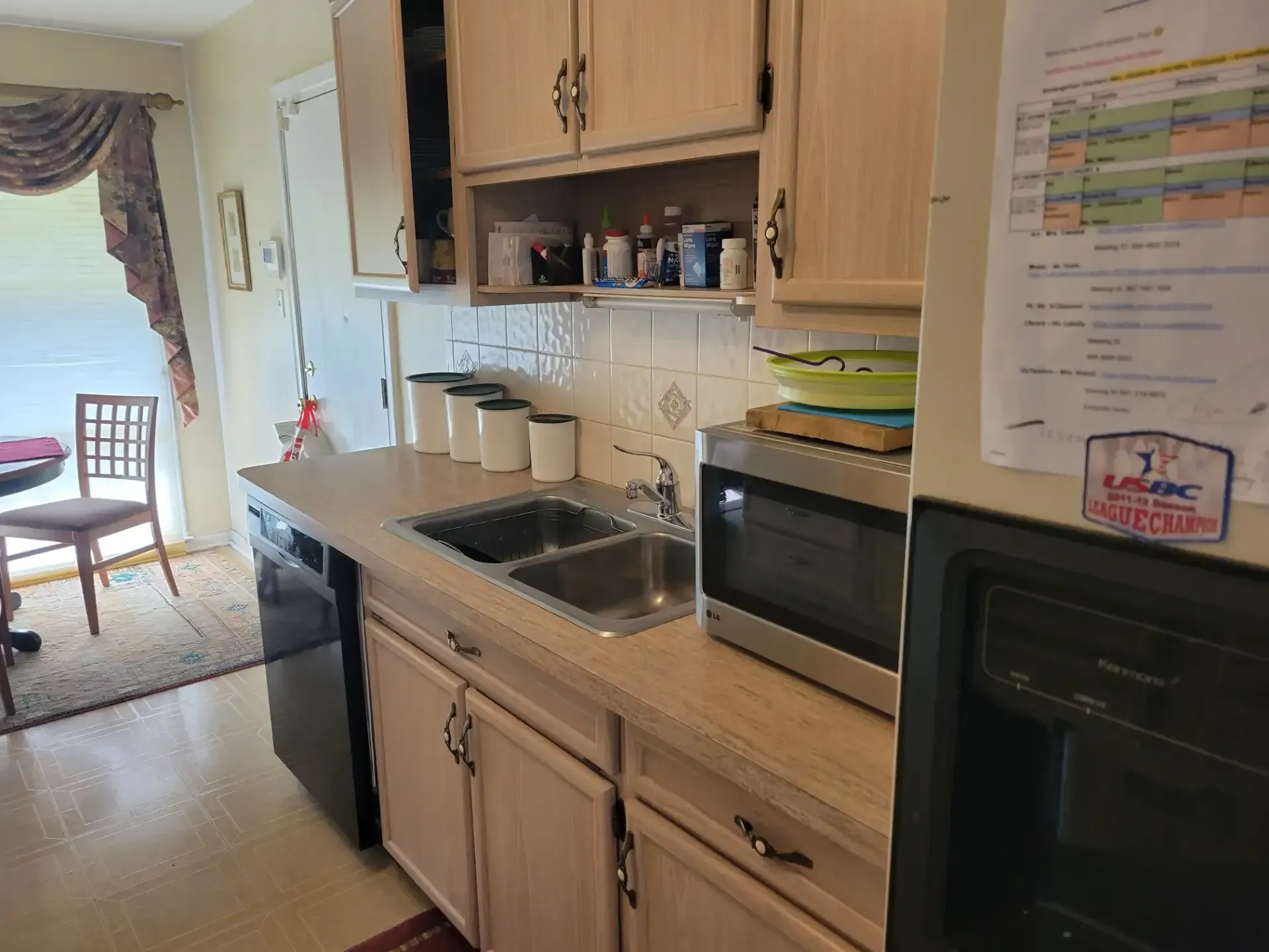 Kitchen with cabinets, sink, dishwasher, and microwave. A doorway and window are visible.