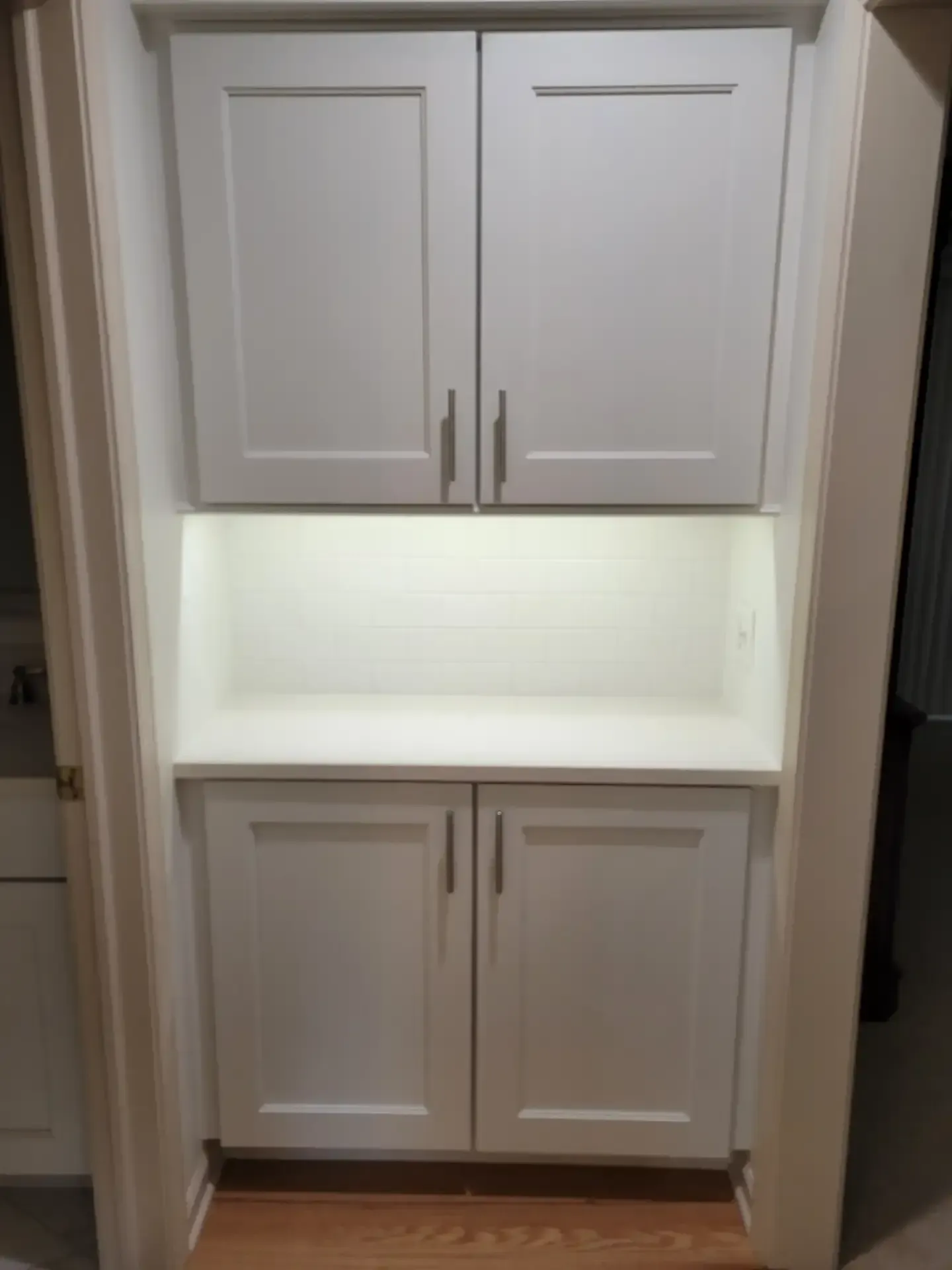 White built-in cabinetry with four doors, countertop, and recessed lighting in a hallway.