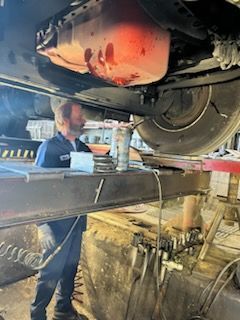 A man is working underneath a car on a lift – Fairfield, AL - Big Moe Spring & Alignment of B'Ham