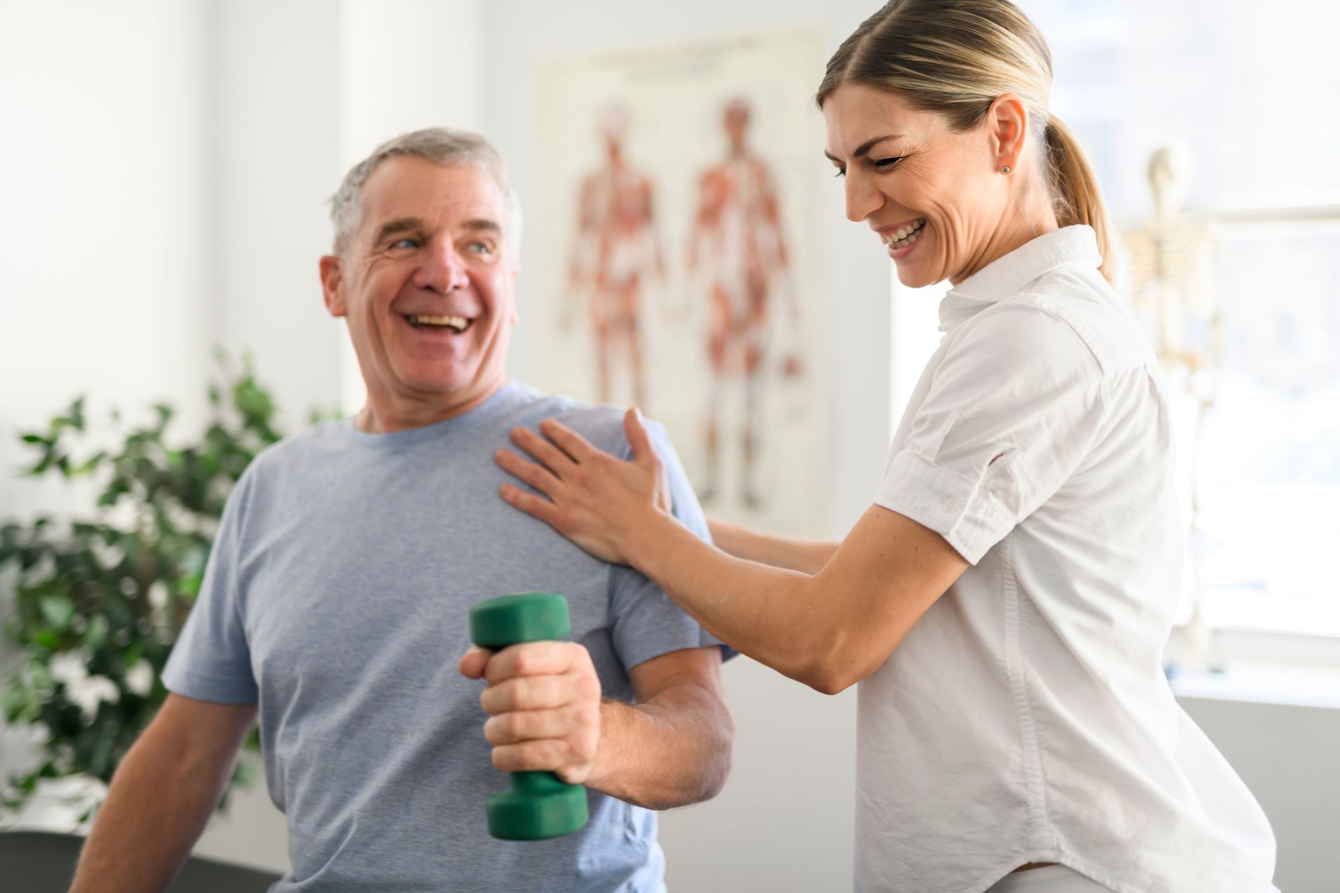 A woman is helping an older man lift a green dumbbell.