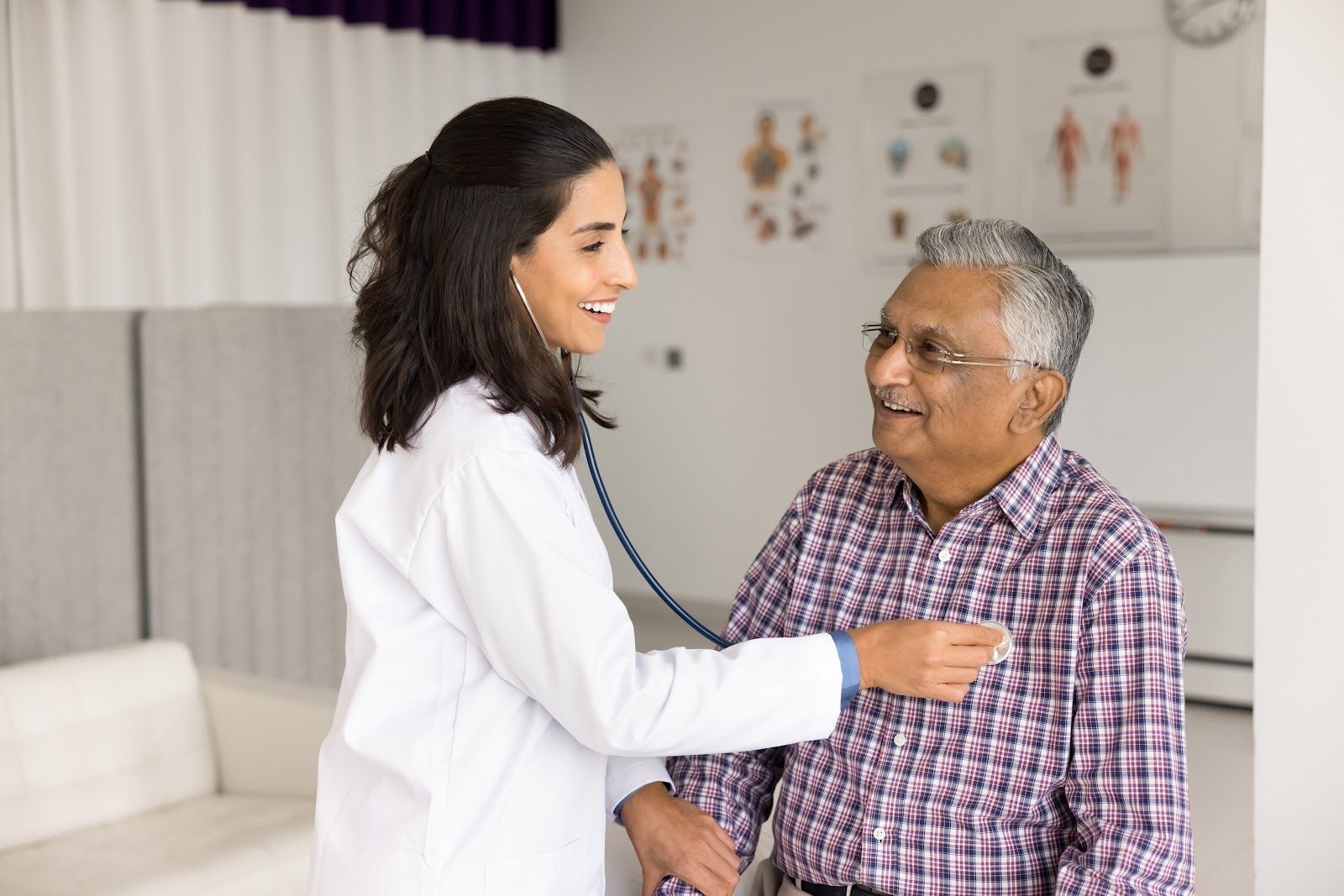 Doctor listening to a patient's chest with a stethoscope in a medical office.