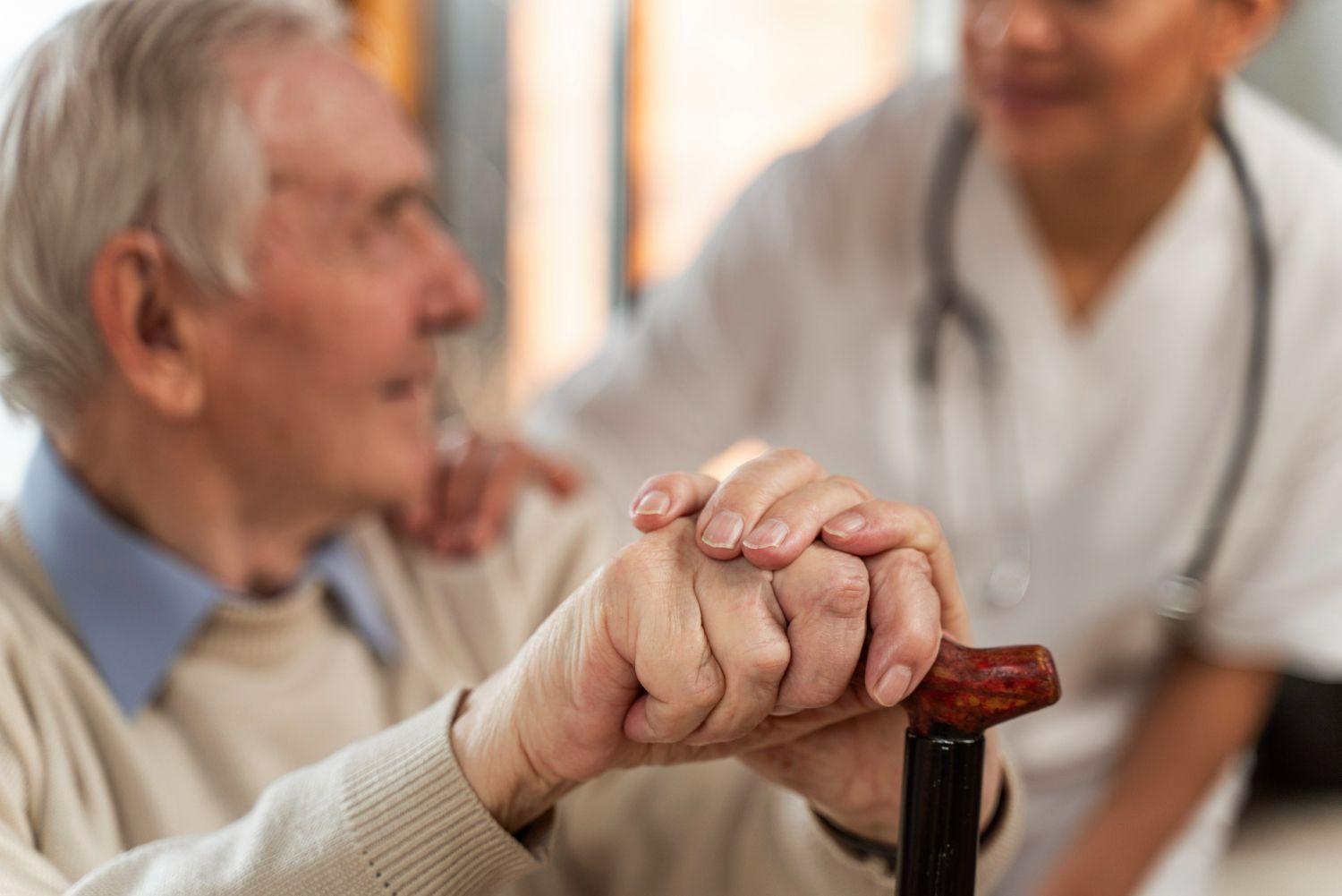 An elderly man is holding a nurse 's hand while holding a cane.