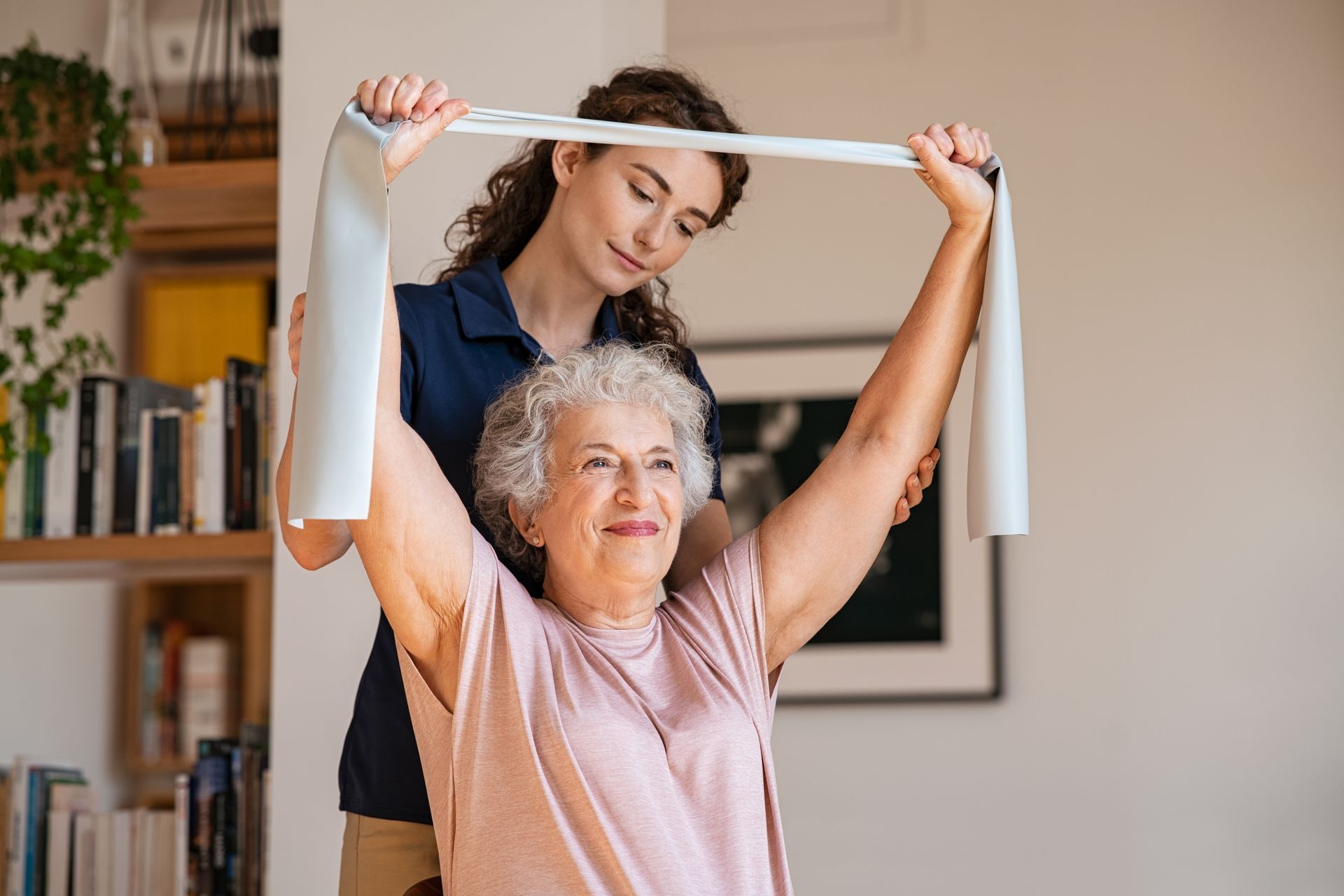 A woman is helping an elderly woman with a resistance band.