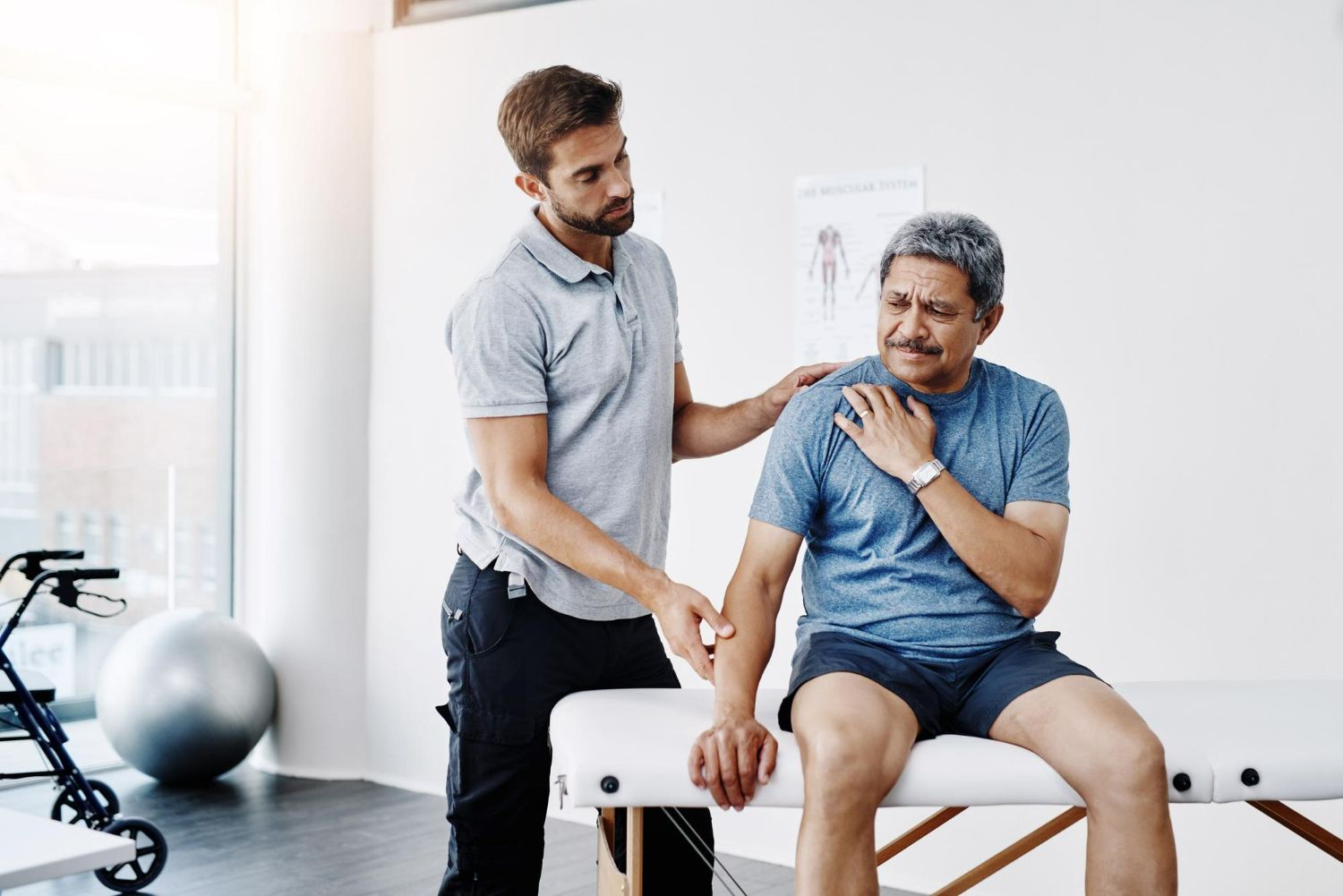 Physical therapist supporting seated patient in a bright clinic room