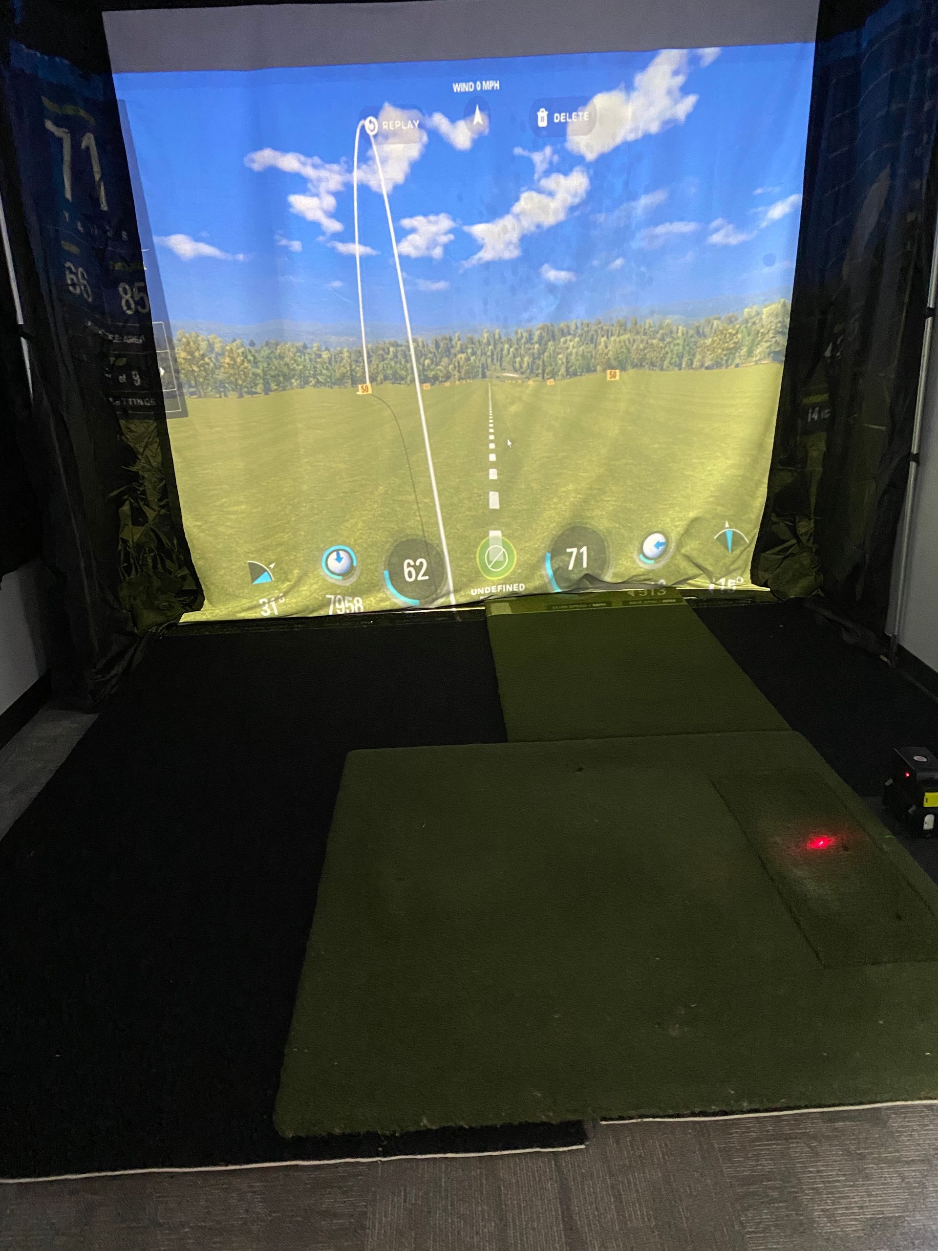 A golf simulator with a large screen on the wall.