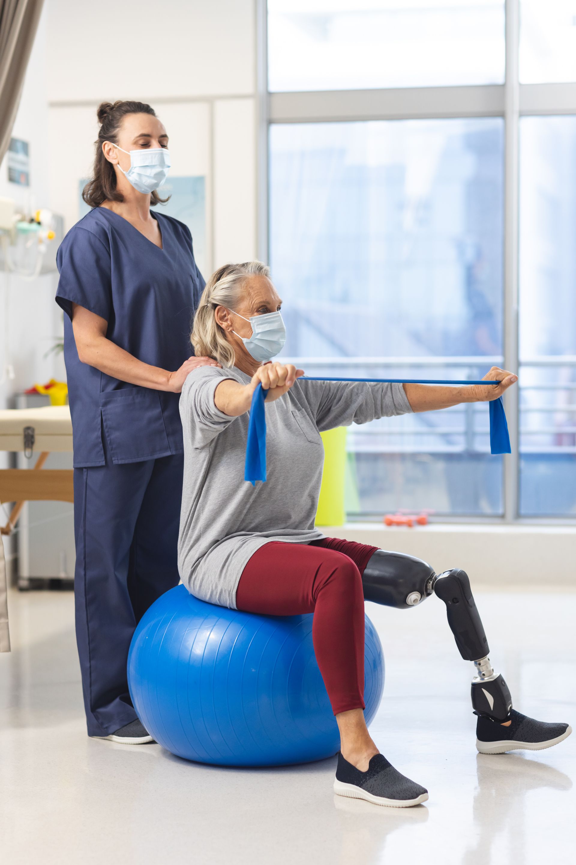 A woman with a prosthetic leg is sitting on a blue exercise ball.