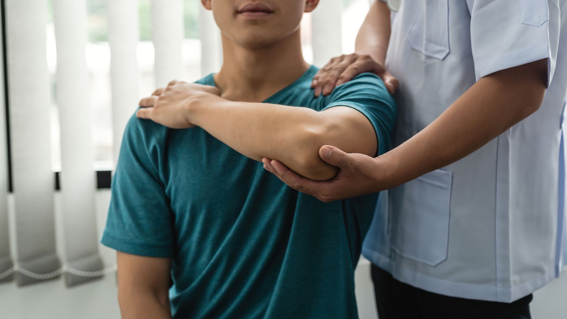 A man is getting his shoulder examined by a doctor.