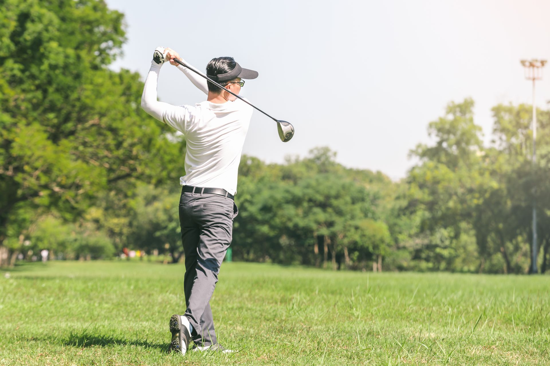 A man is swinging a golf club on a golf course.