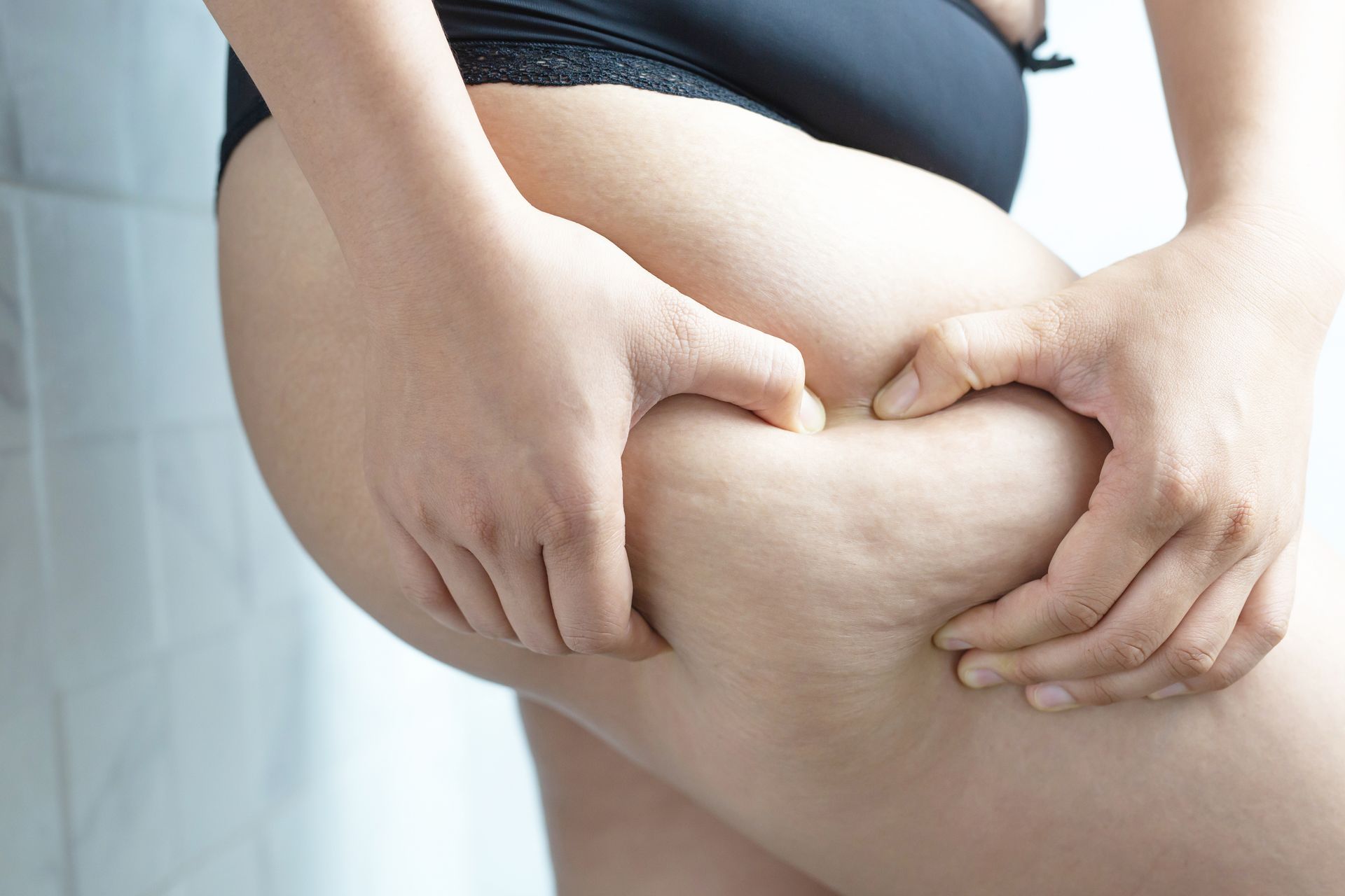 A woman is holding her thigh with her hands.
