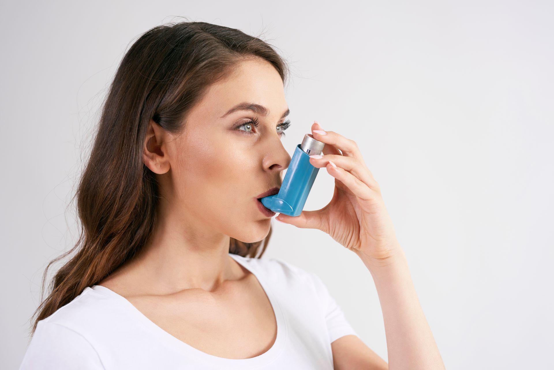 A woman is using an inhaler to treat her asthma.