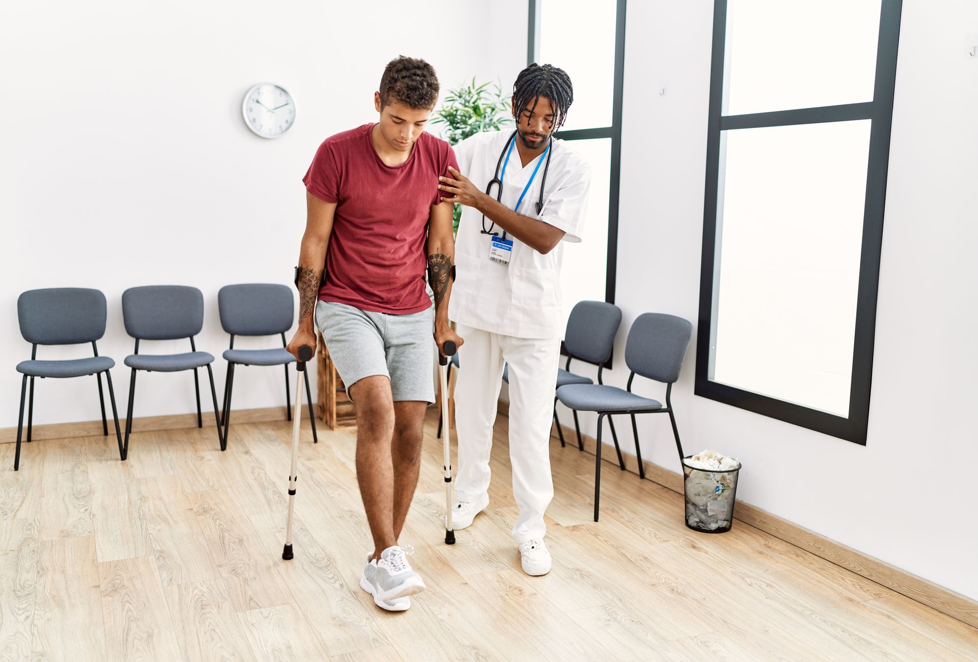 A man with crutches is being helped by a doctor in a waiting room.