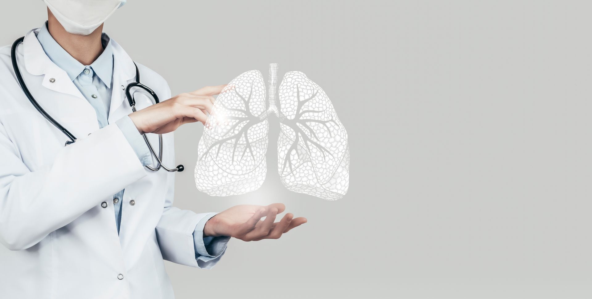 A doctor wearing a mask is holding a picture of lungs in his hands.