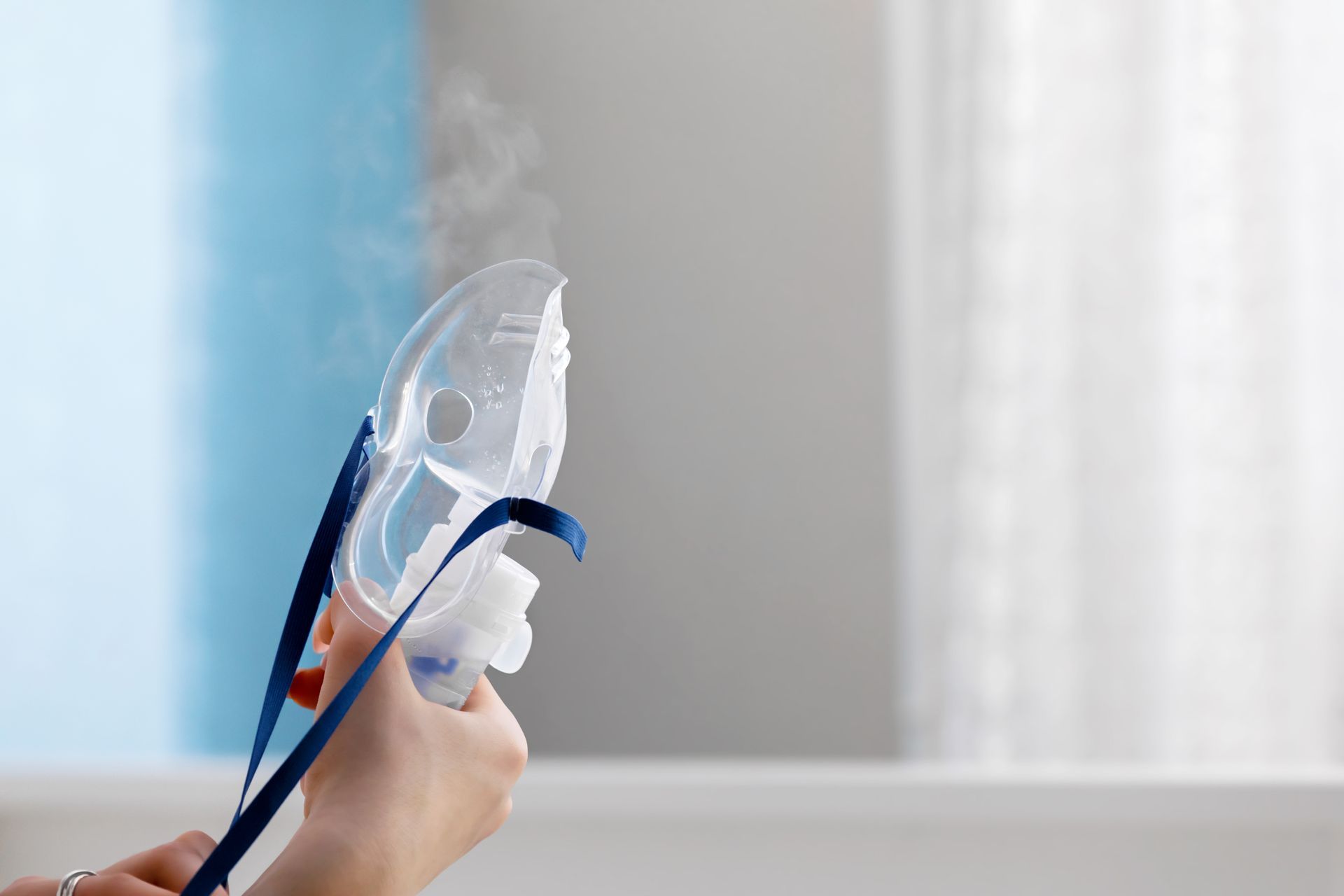 A person is holding an oxygen mask with steam coming out of it.