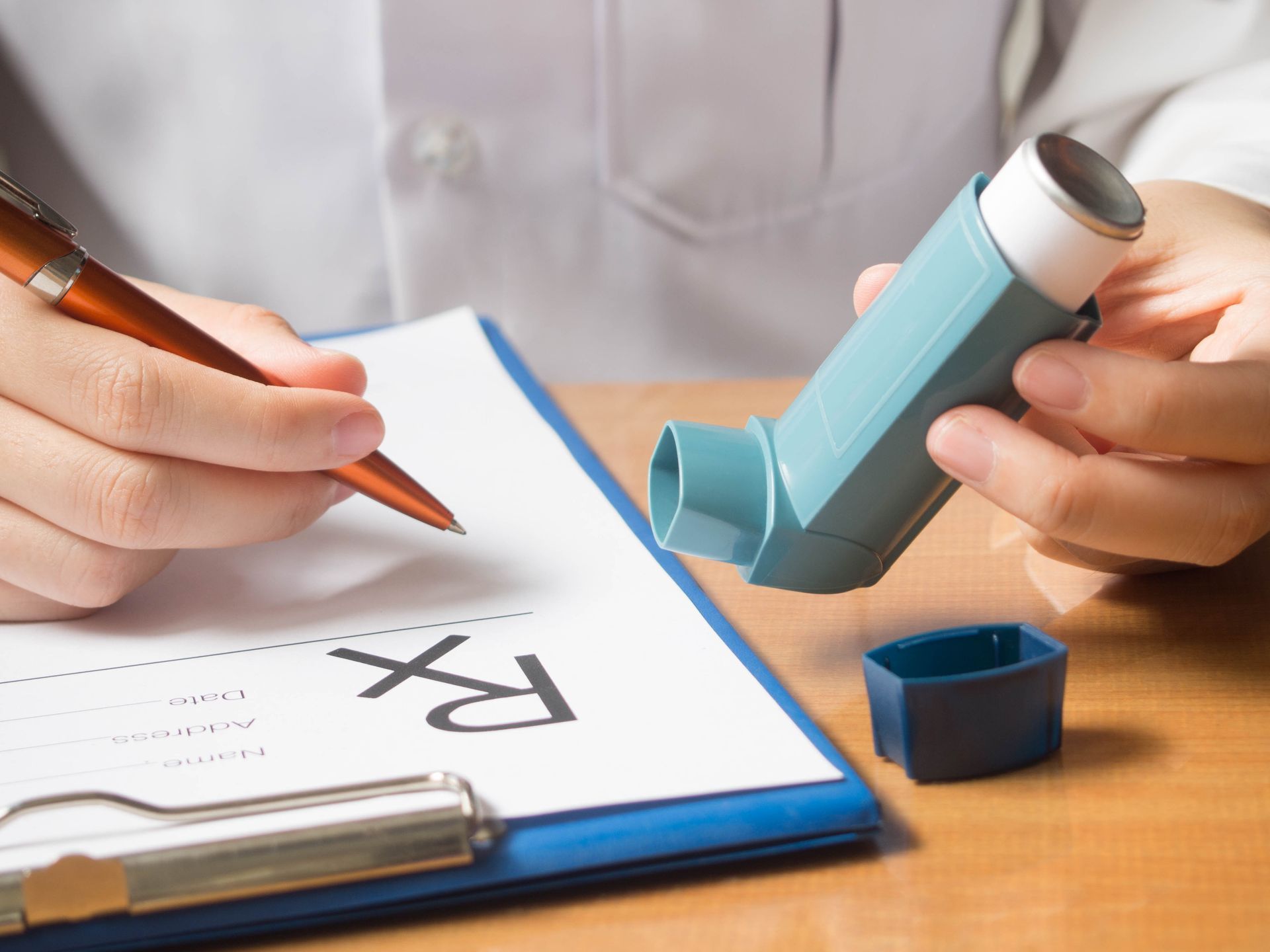 A person is writing on a clipboard while holding an inhaler