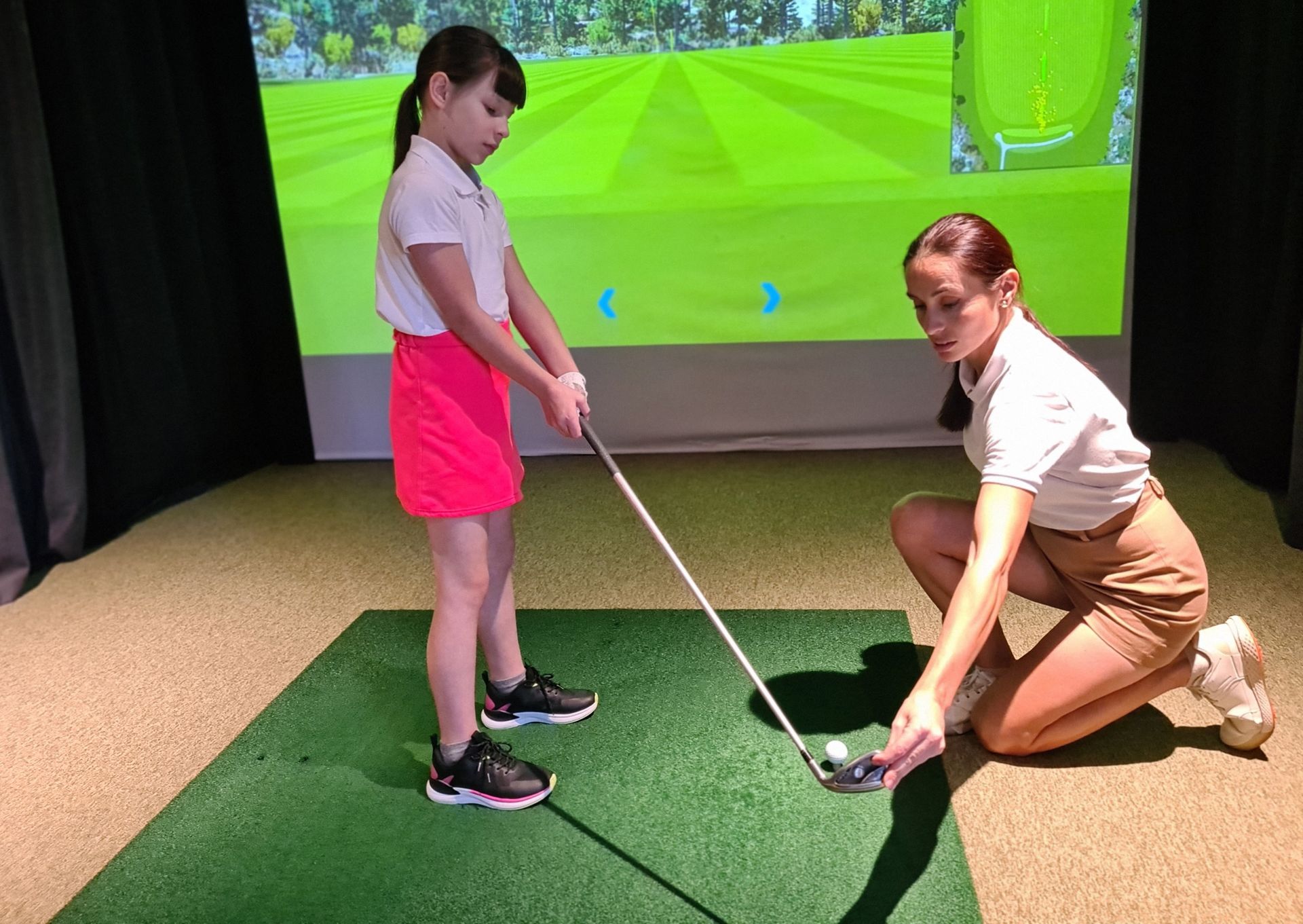 A woman is teaching a young girl how to play golf.