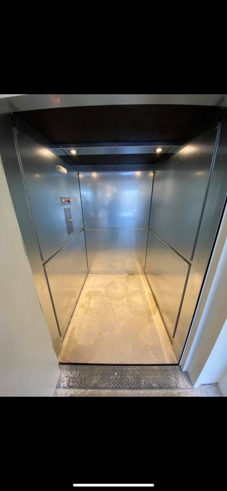 Un gros plan d'un ascenseur en acier inoxydable avec un sol en béton.