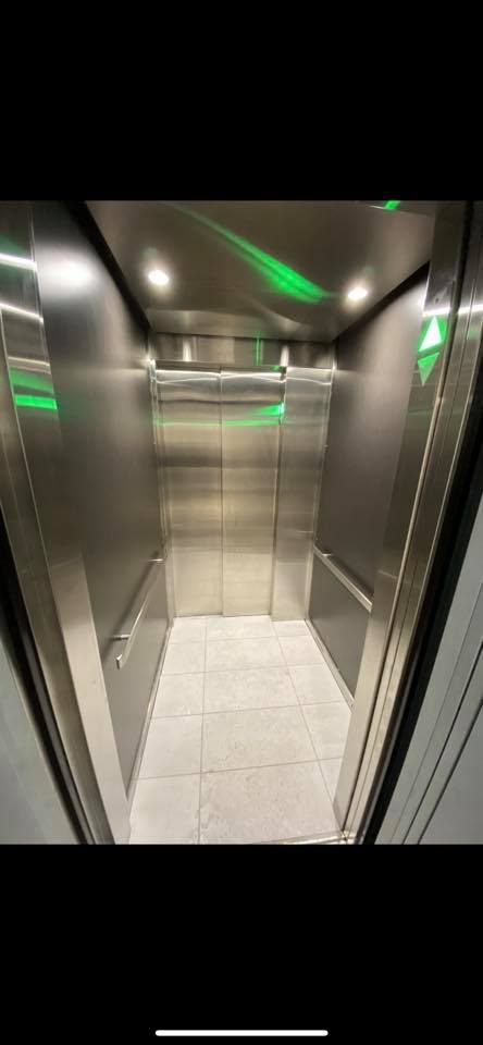 Un ascenseur en acier inoxydable avec un feu vert au plafond.