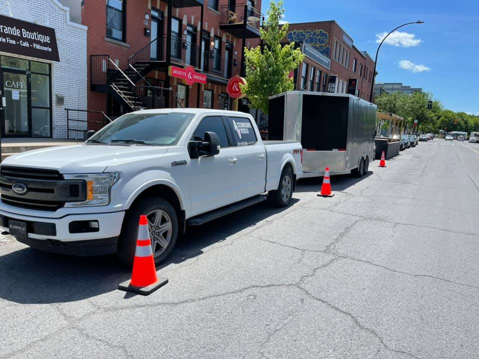 Un camion blanc est garé sur le bord de la route à côté d'une remorque.