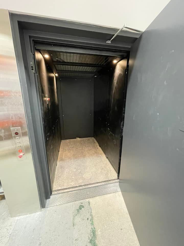 Un ascenseur noir avec une porte ouverte dans un immeuble.