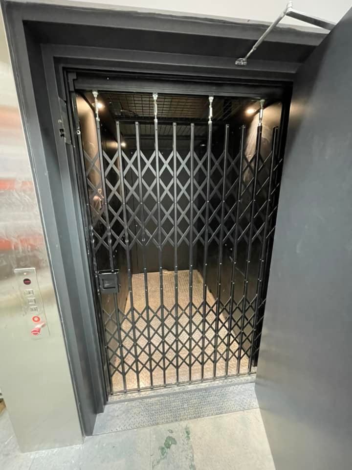 Un ascenseur noir avec un portail noir et une porte ouverte.