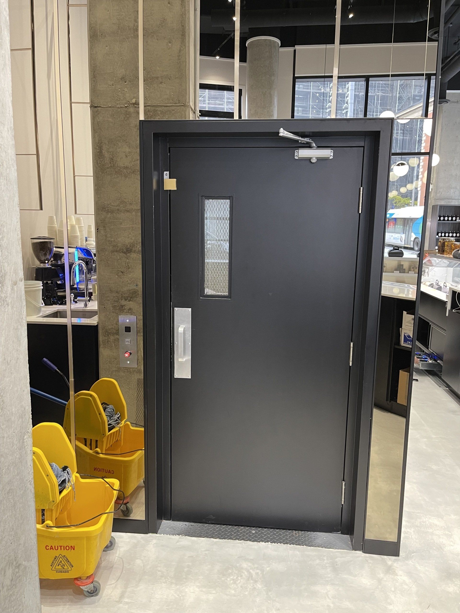 Une porte noire dans une pièce avec des paniers à vadrouille jaunes