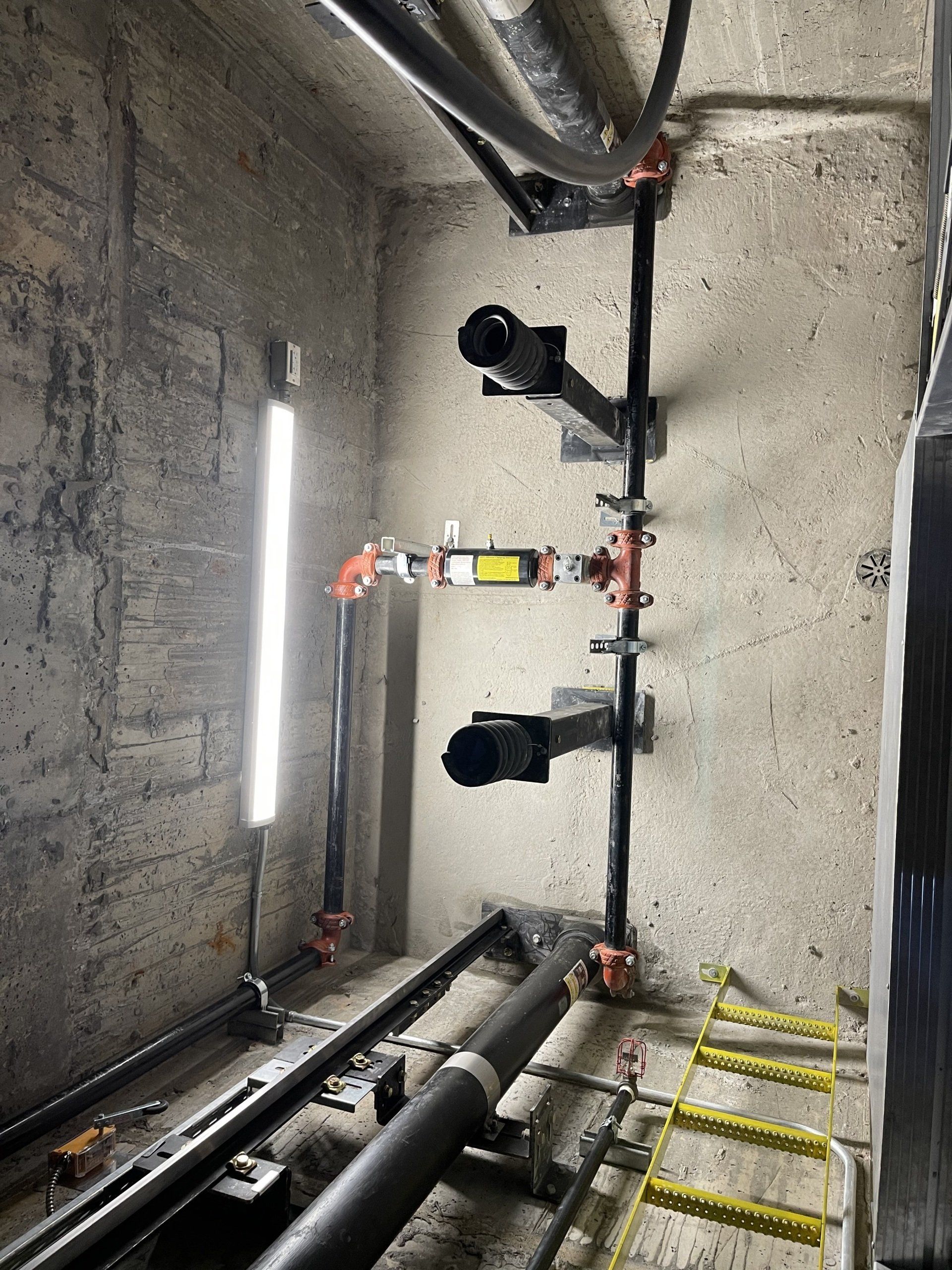 Une pièce avec beaucoup de tuyaux suspendus au plafond.