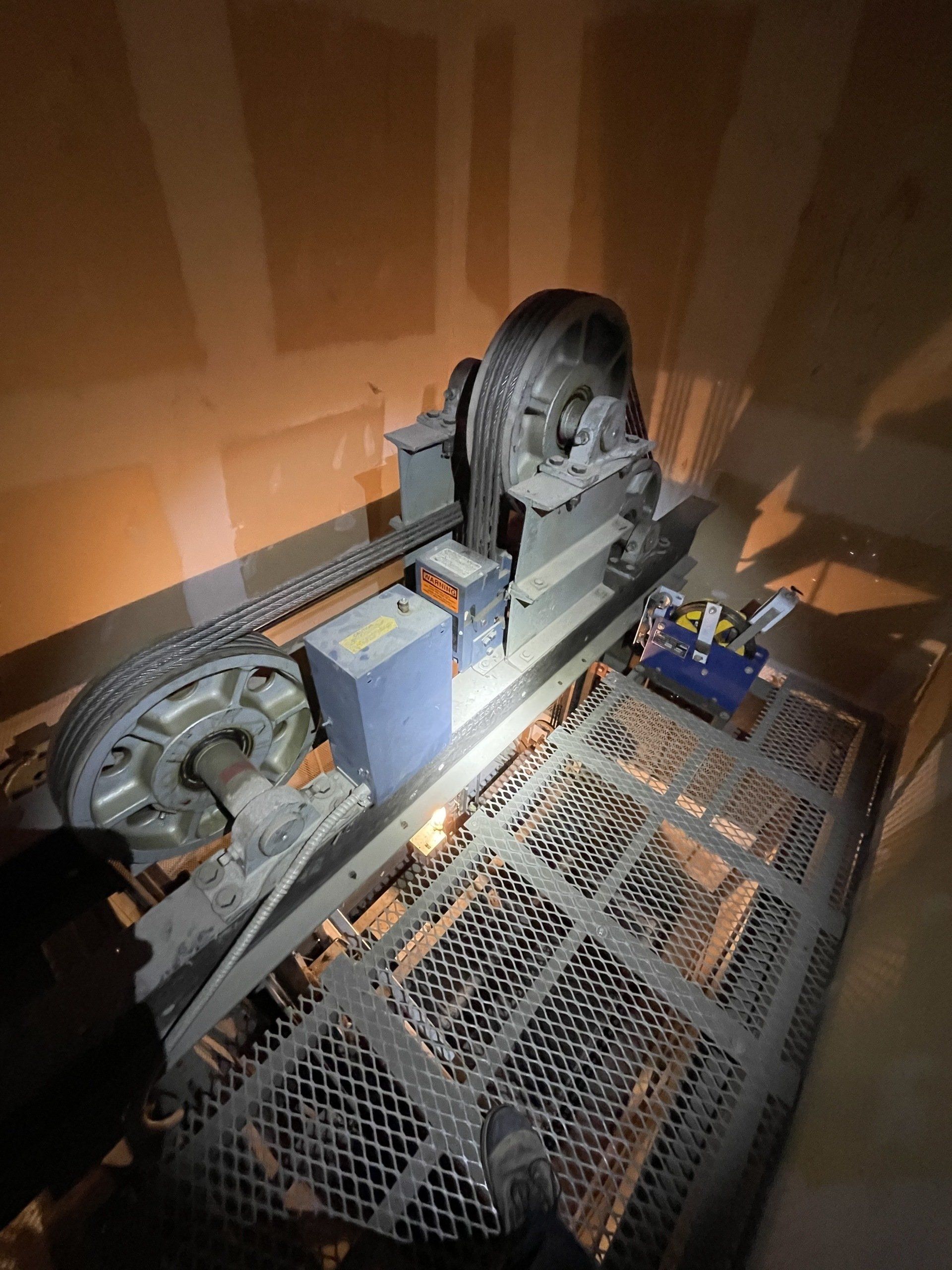 Une personne travaille sur une machine dans un ascenseur.