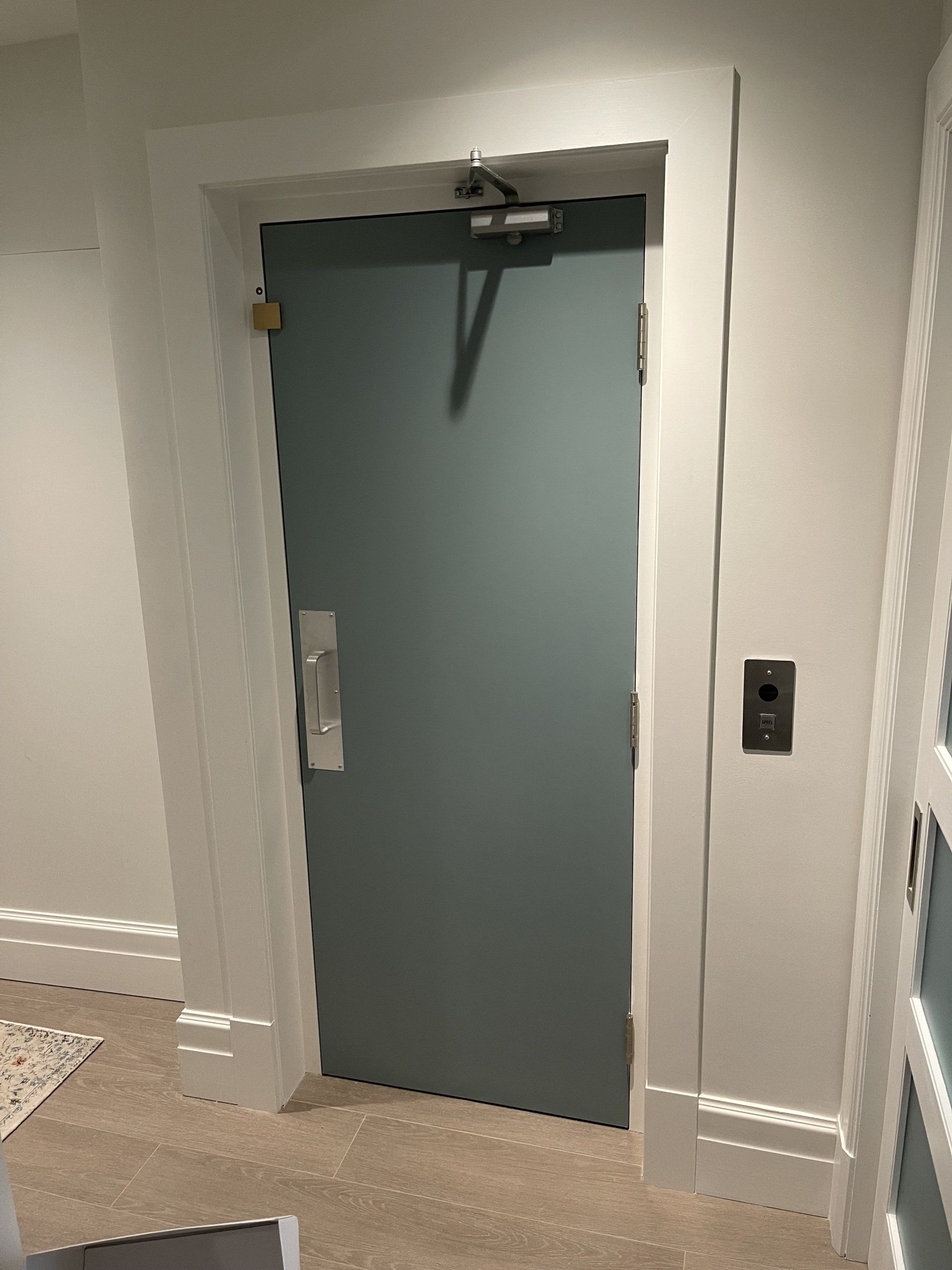 Une porte bleue se trouve dans un couloir à côté d'un mur blanc.