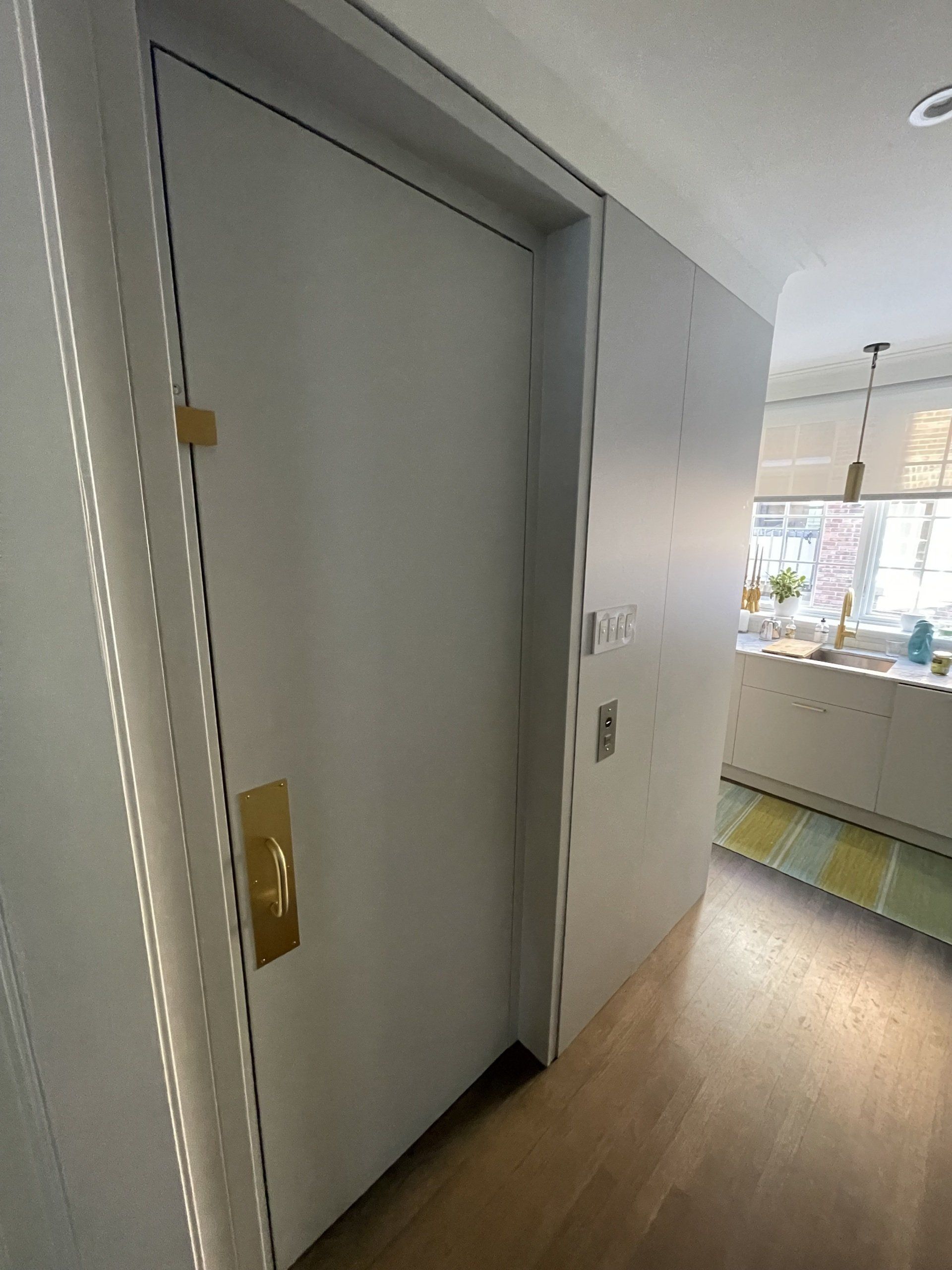 Une porte blanche avec une poignée dorée dans un couloir