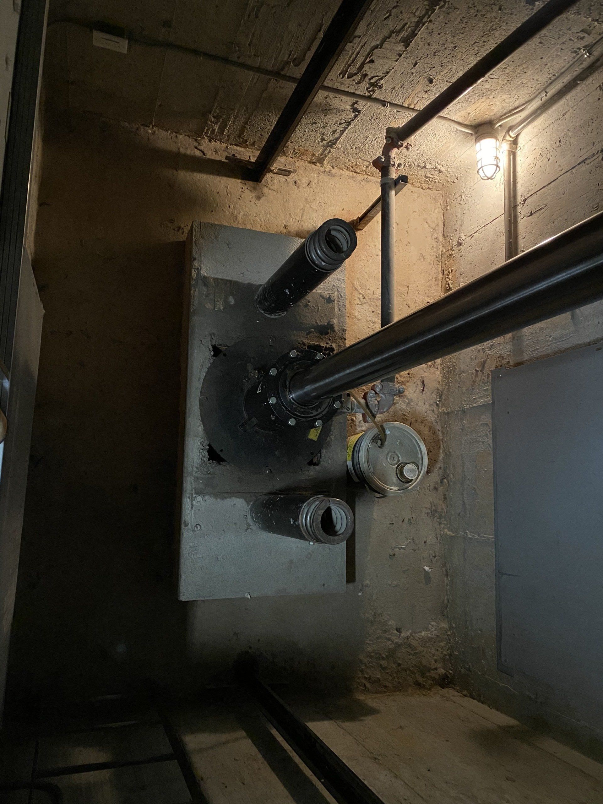 Une pièce sombre avec beaucoup de tuyaux et une lumière au plafond