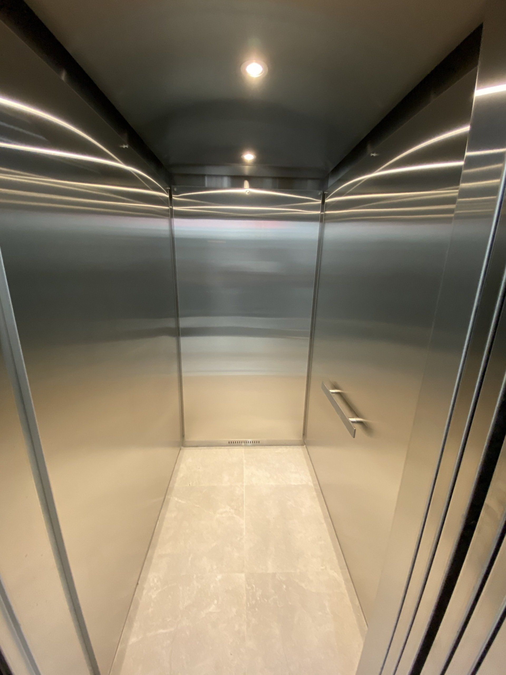 Un ascenseur en acier inoxydable avec un sol blanc