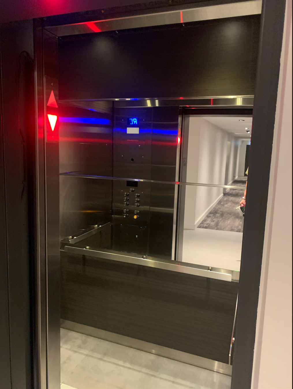 Intérieur d'un ascenseur, avec murs en acier inoxydable et blancs, avec éclairage zénithal.