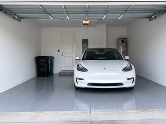 A White tesla sitting in a garage epoxy floor
