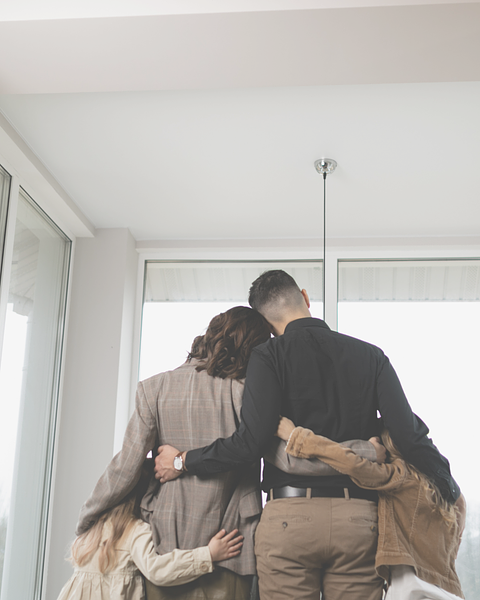 Family of four embracing, looking out a window.
