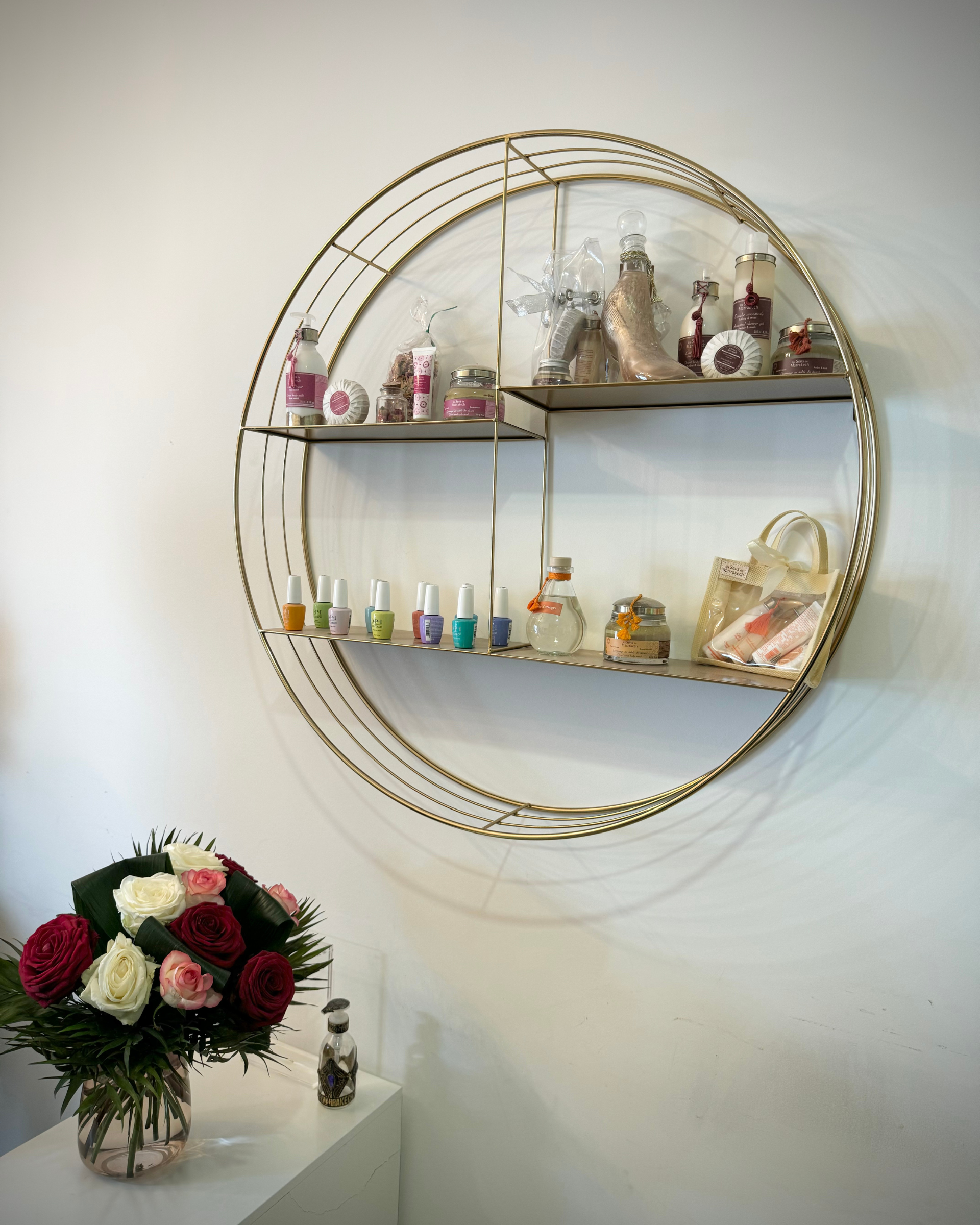 Une étagère avec des produits de manucures avec un vase de fleurs devant