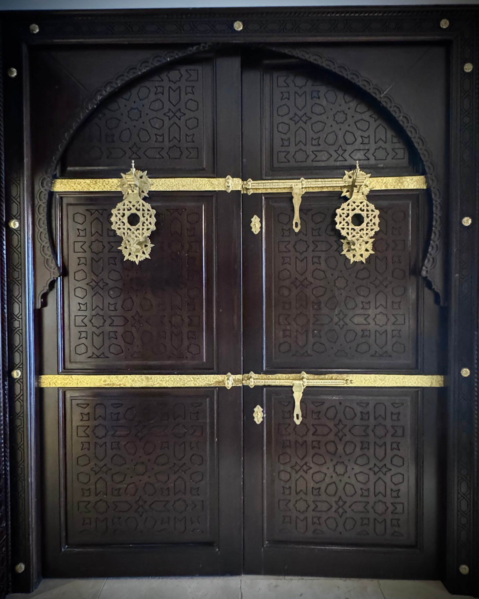 Une porte en bois sombre avec une bordure dorée et un motif dessus