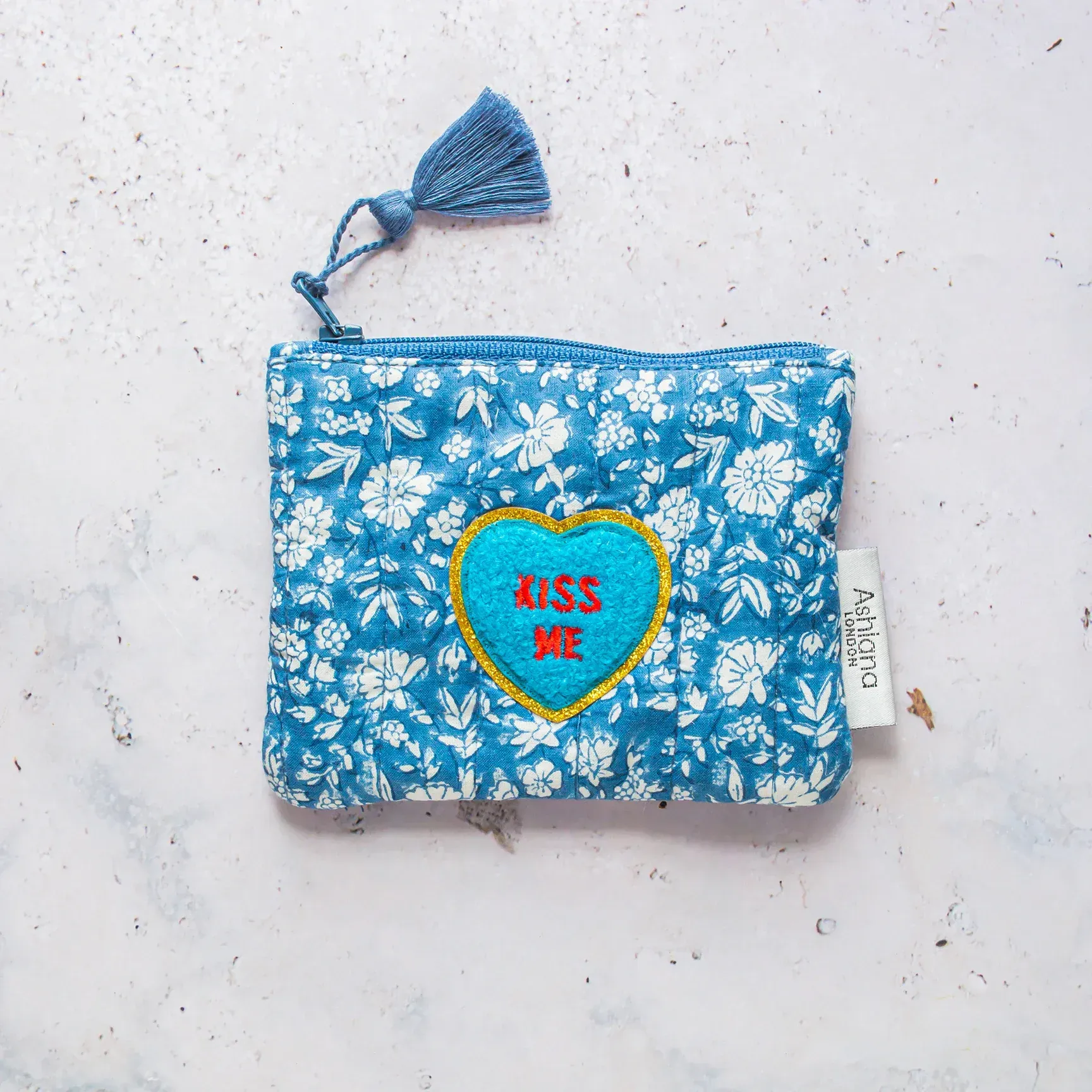 A blue purse with a heart that says kiss me on it