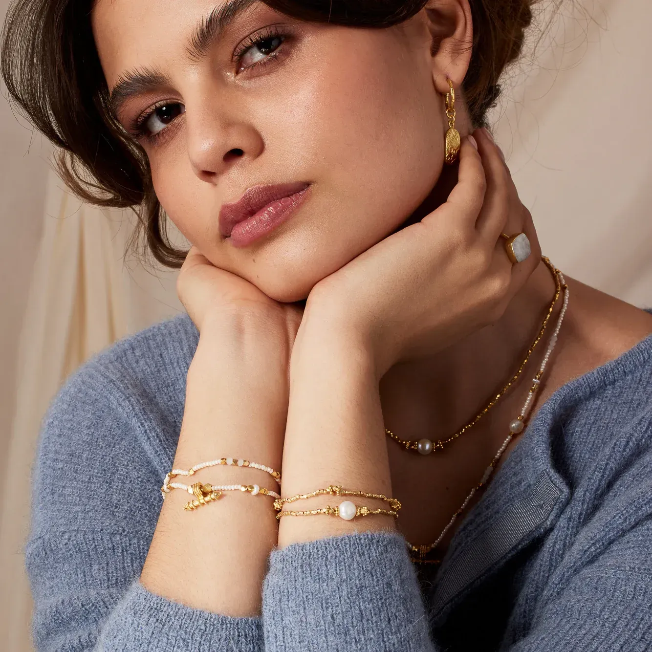 A woman wearing a blue sweater and gold jewelry
