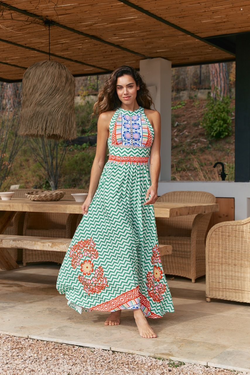 A woman in a long green dress is standing in front of a picnic table.