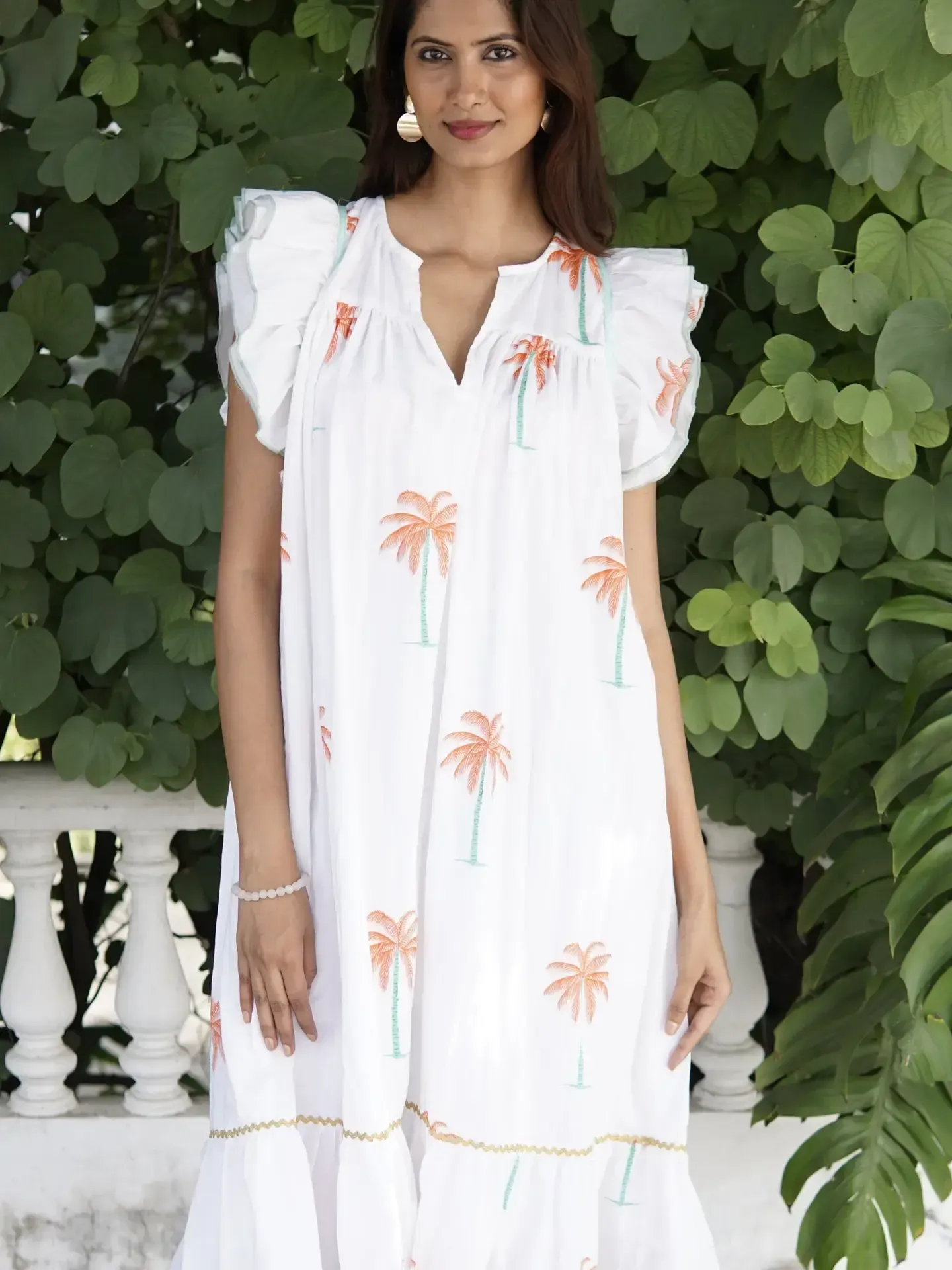 A woman in a white dress with palm trees on it