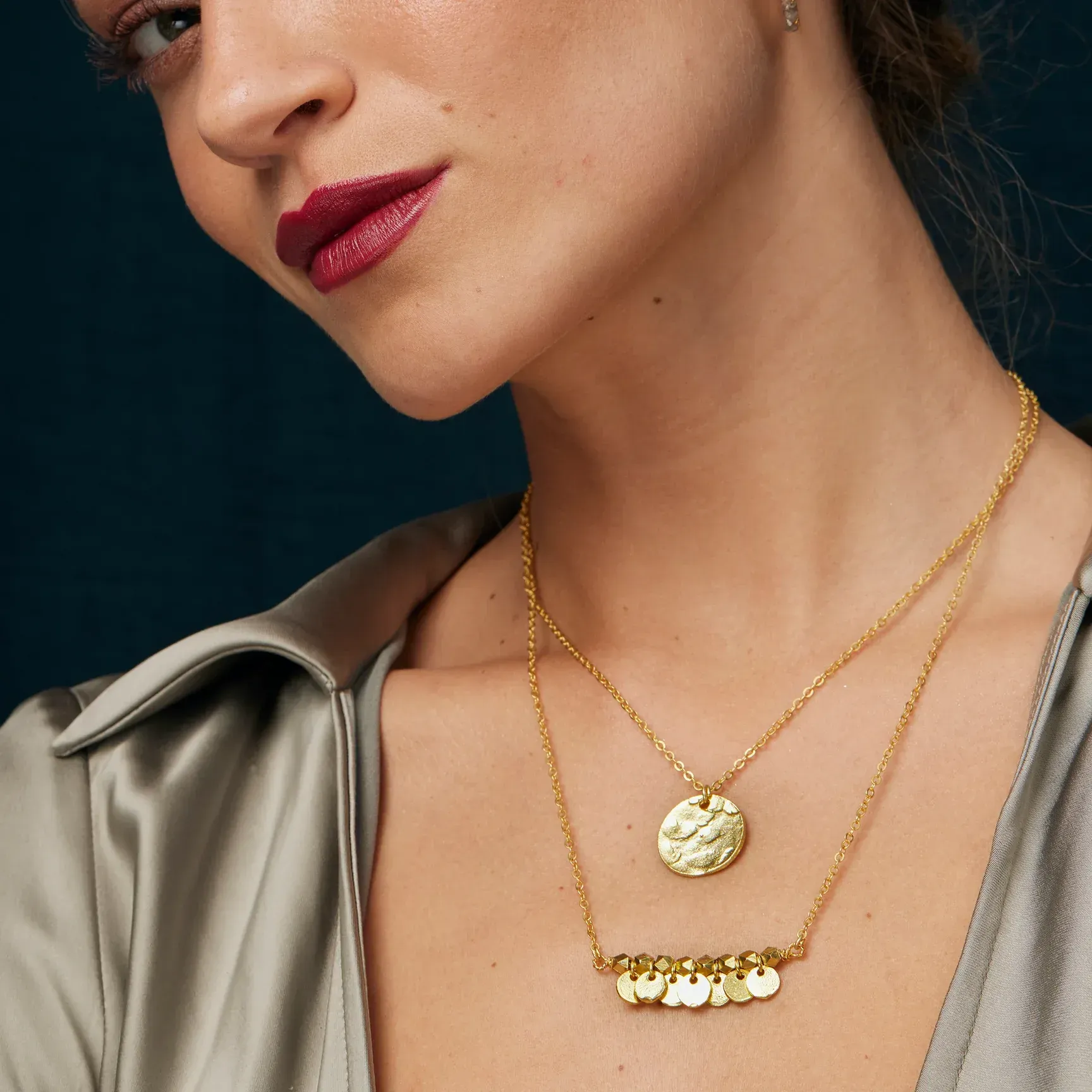 A close up of a woman wearing a gold necklace