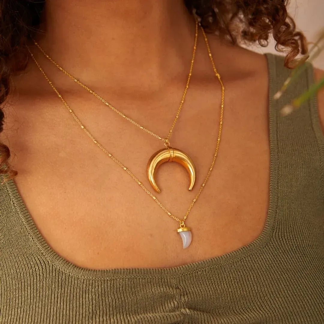 A woman wearing a necklace with a crescent moon pendant